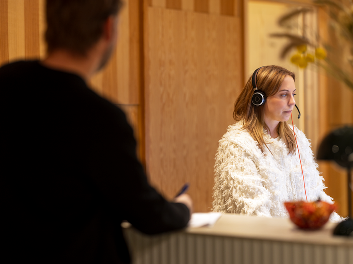 Kvinna sitter i en reception och pratar i telefon