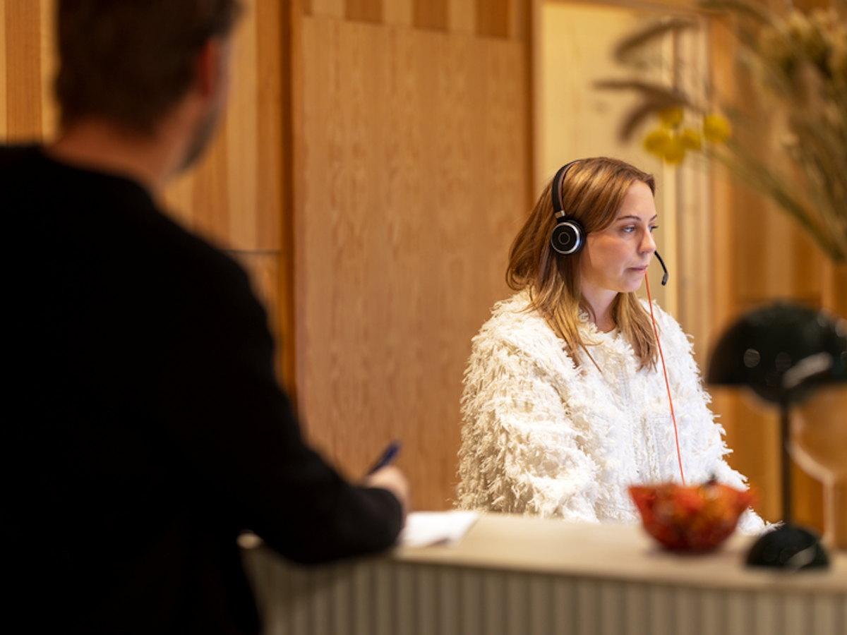 Kvinna sitter i en reception och pratar i telefon