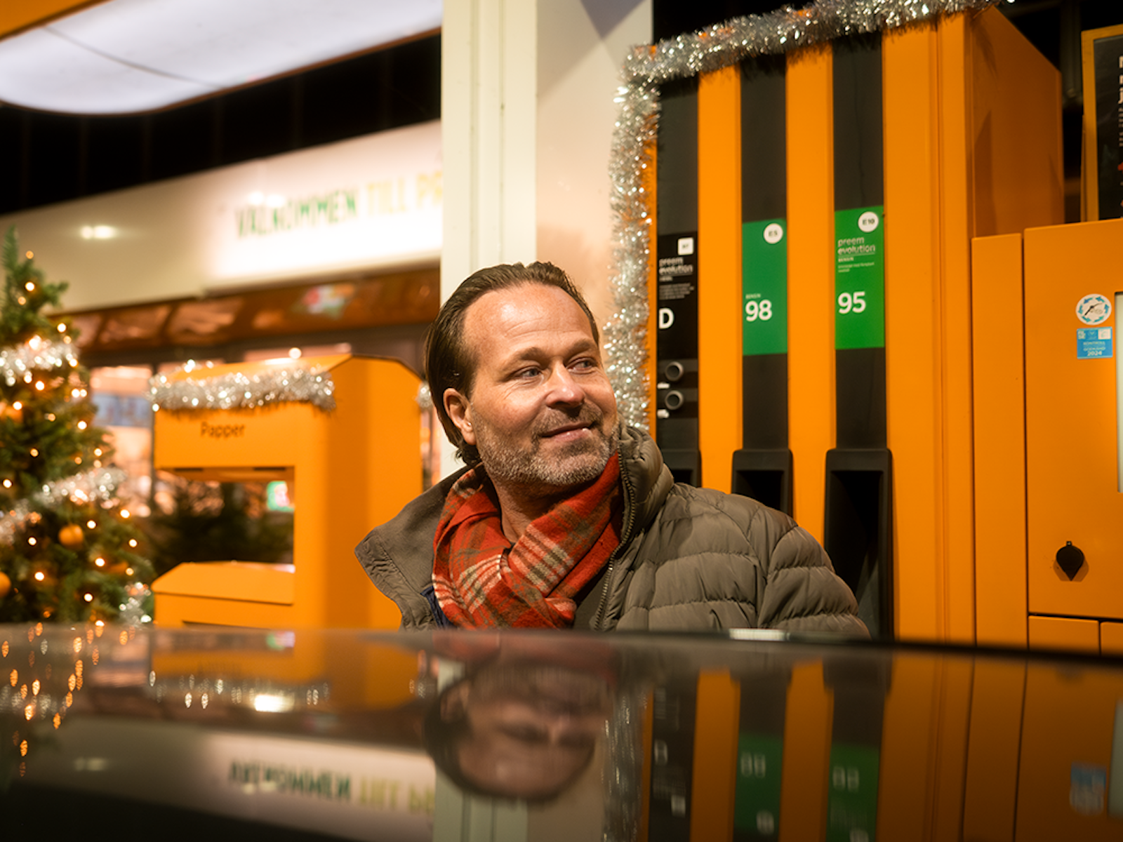 Glad man som tankar på en bensinstation i juletider