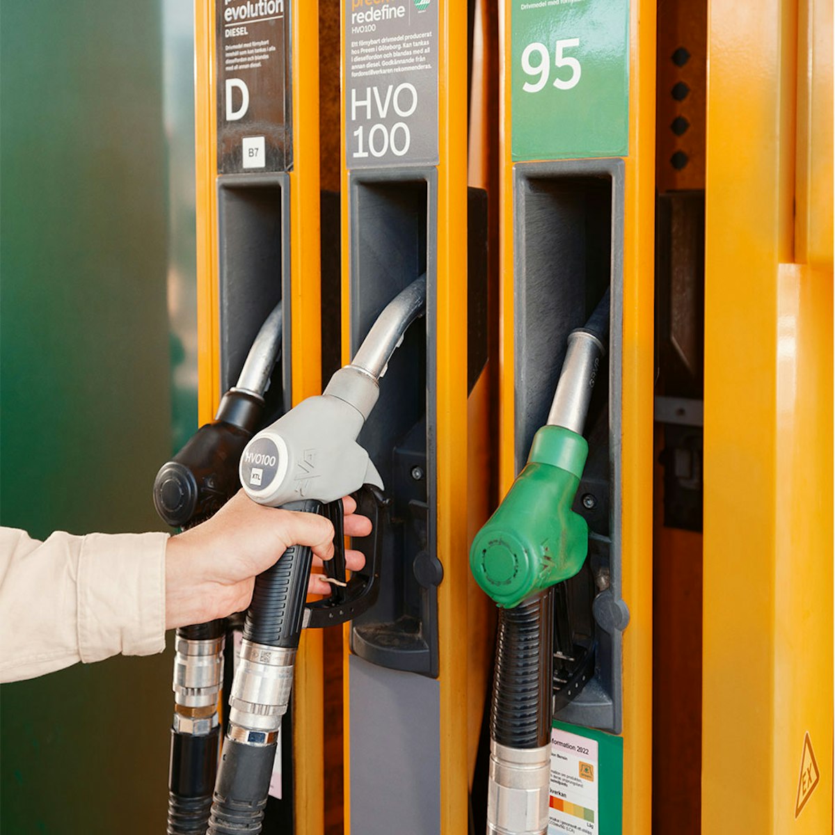 En person håller i ett pumphandtag på station