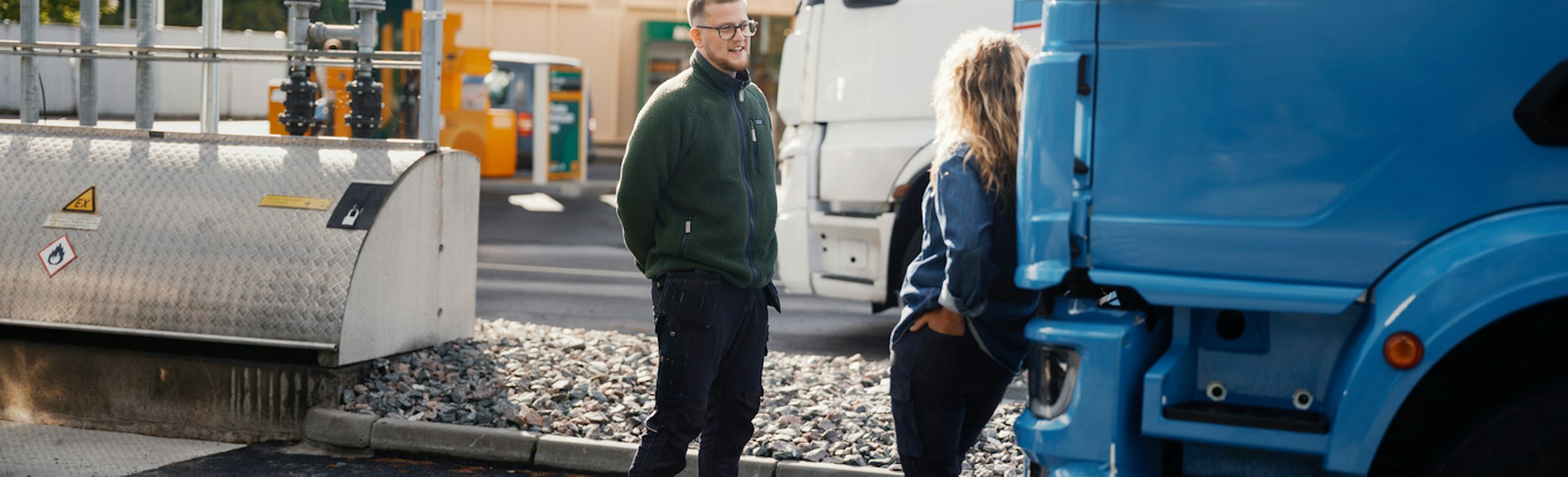 Två personer tankar sina lastbilar på station