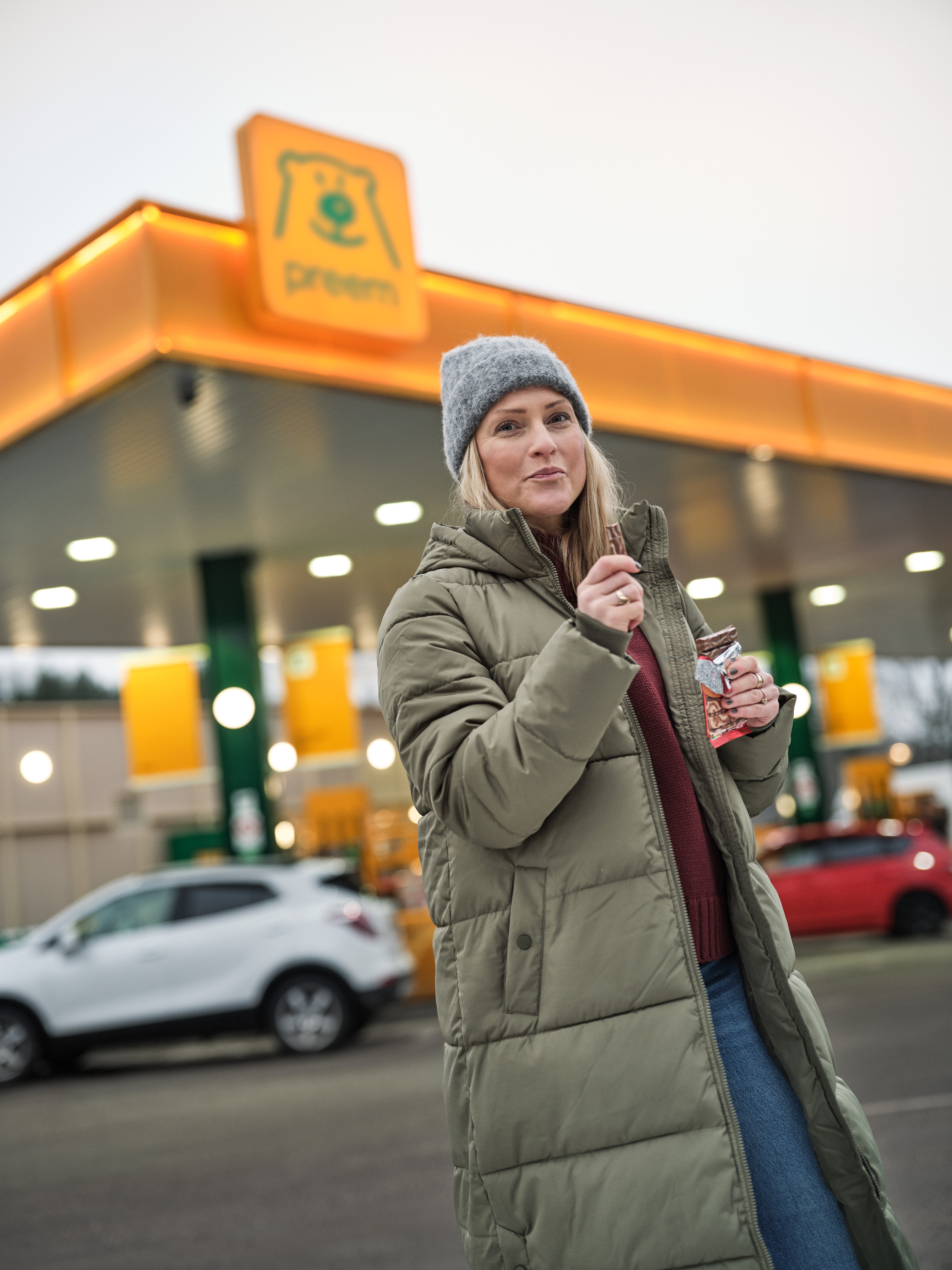 Kund står på plattan vid stationen och äter en chokladkaka