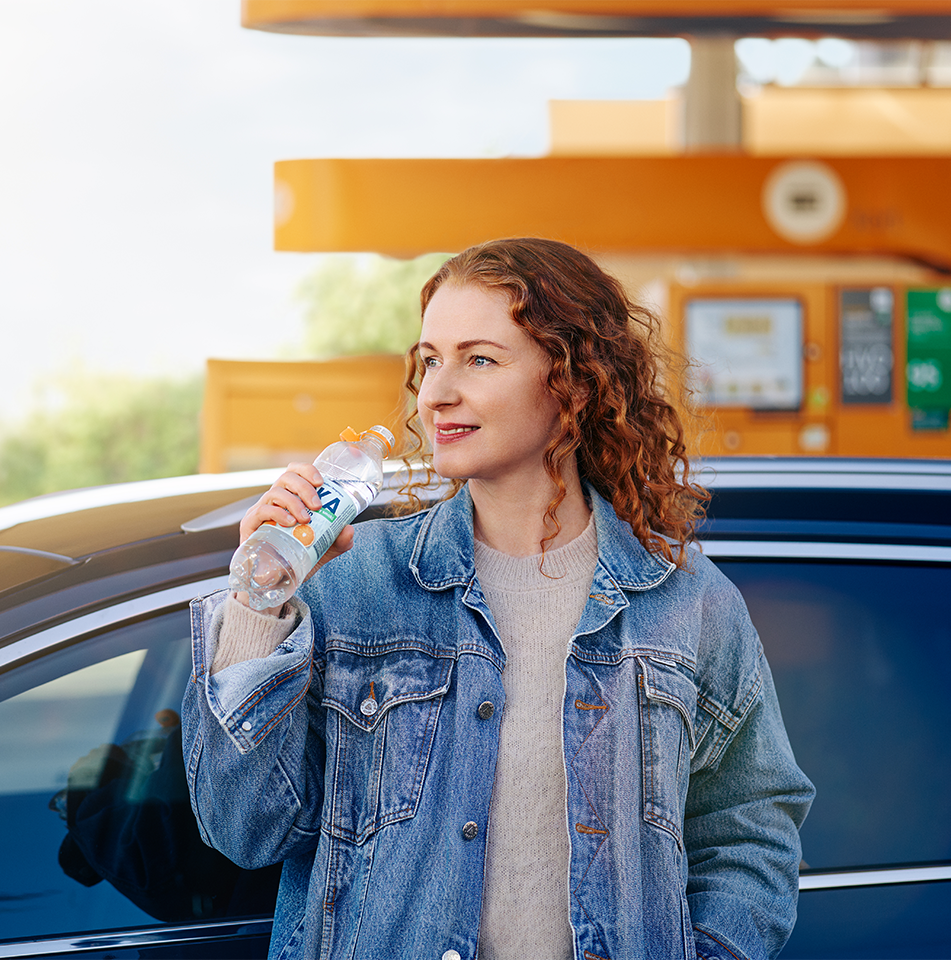 Kvinna står på station och håller i en flaska Loka