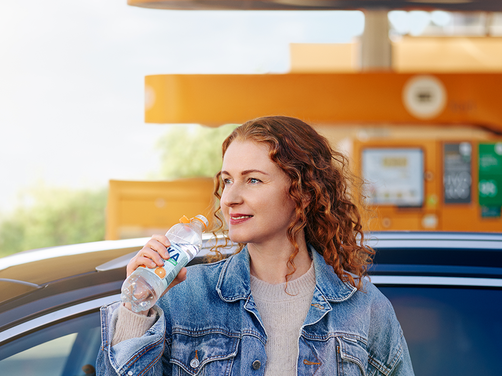 Kvinna står på station och håller i en flaska Loka