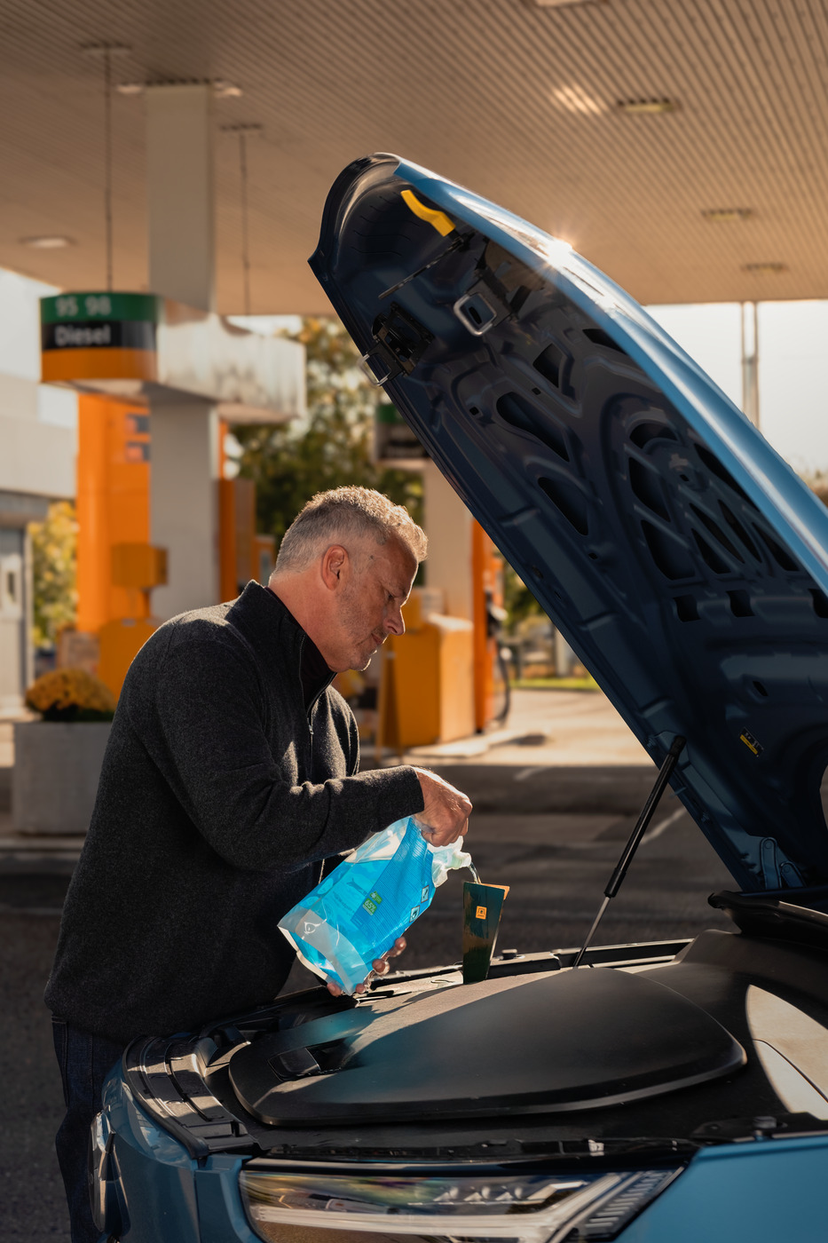 Man fyller på spolarvätska