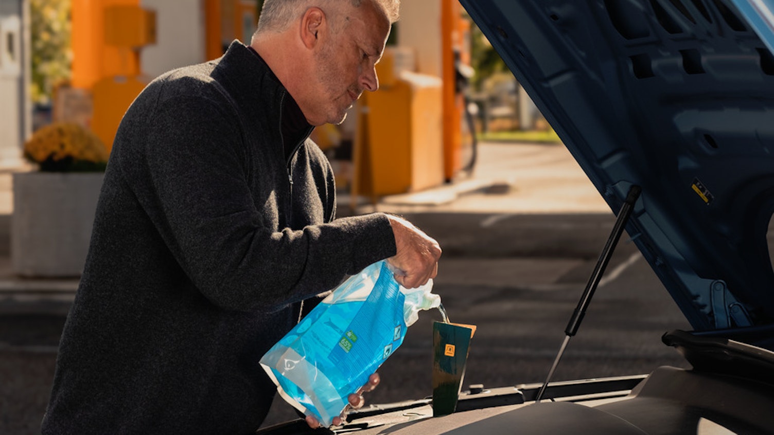 Man fyller på spolarvätska