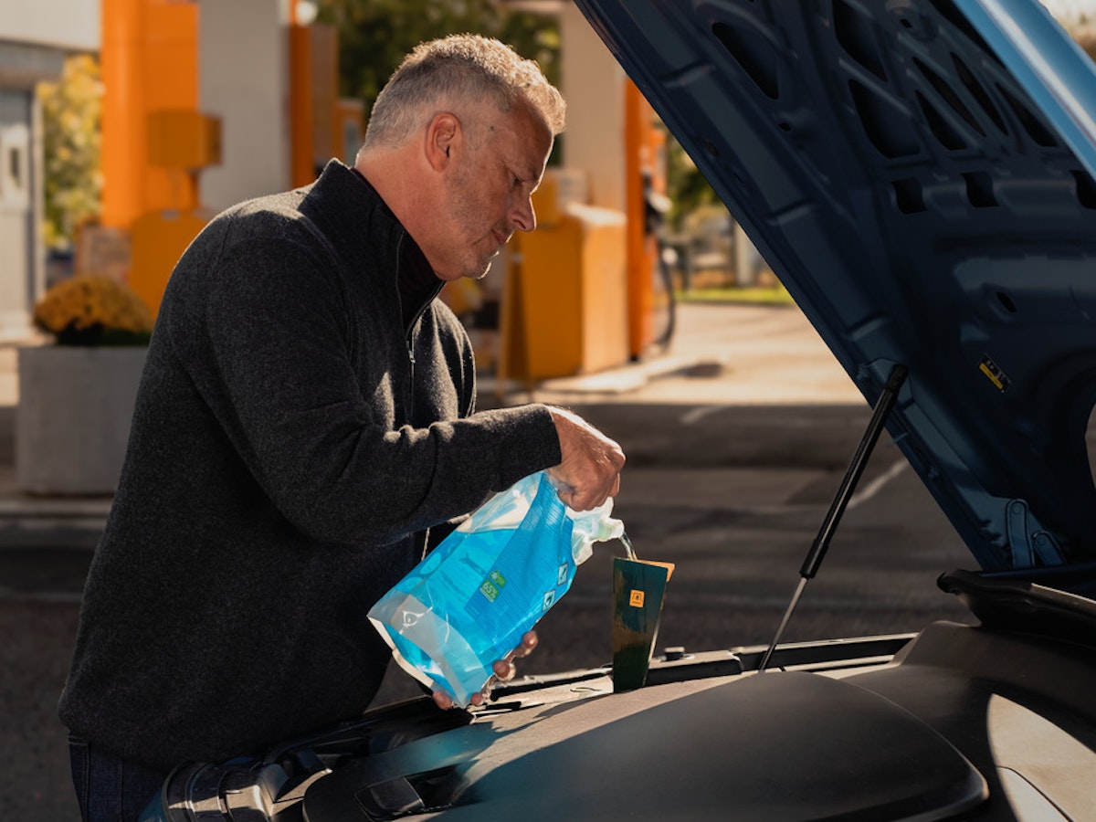 Man fyller på spolarvätska