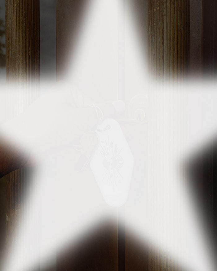 Soft white five-pointed star overlay revealing a hand holding vintage-style keys