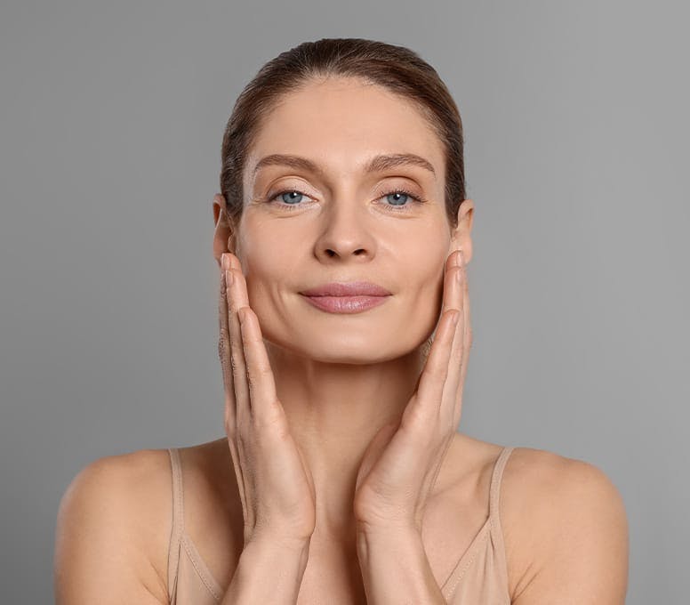 woman with hair up and touching her face