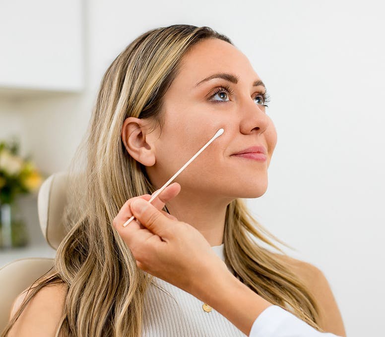 woman in exam chair with q-tip up to her cheek