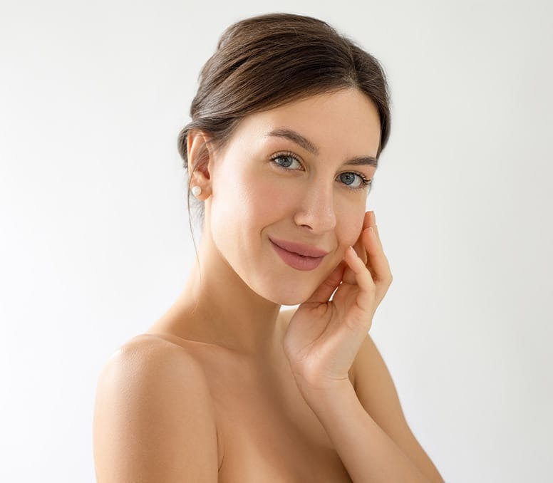 woman smiling and touching her cheek