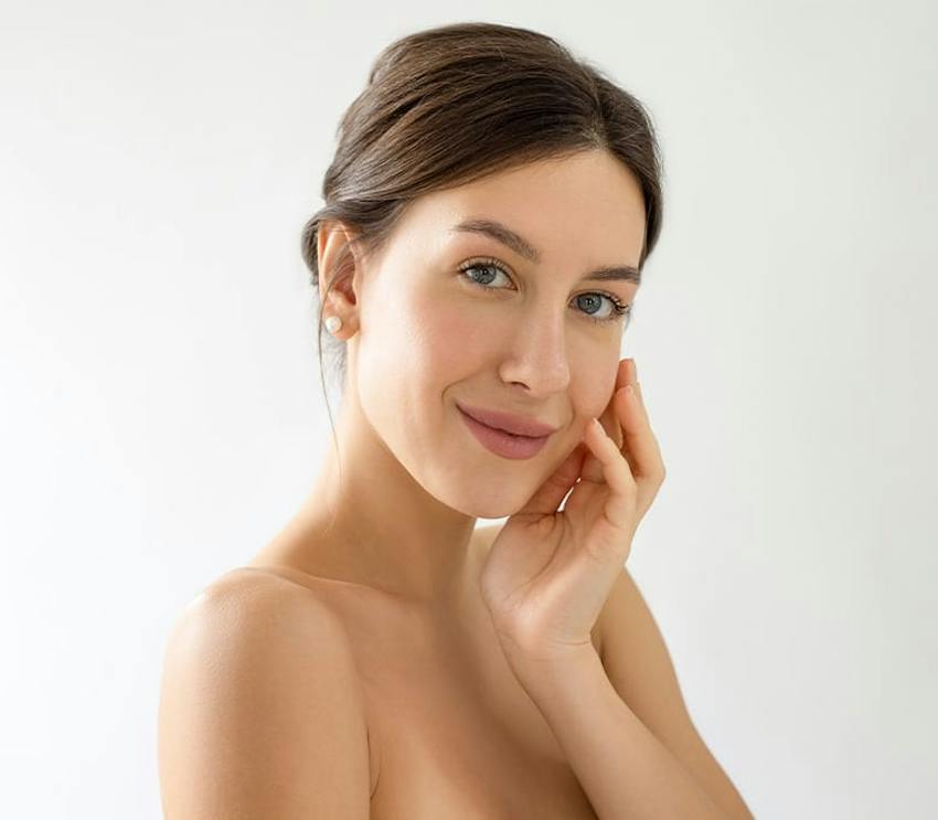 woman smiling and touching her cheek