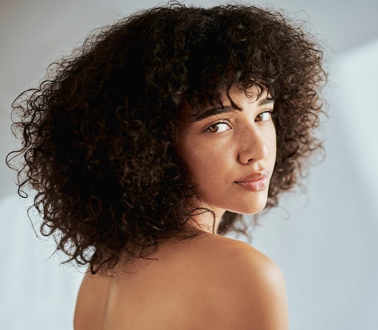 woman with curly afro looking over her shoulder