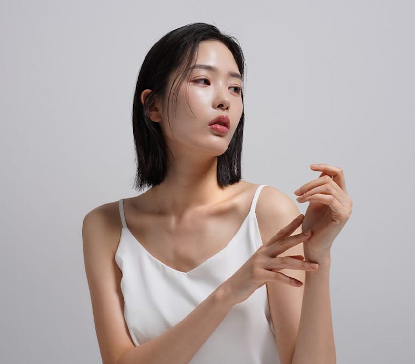 woman in white tanktop touching her other hand and looking to the right