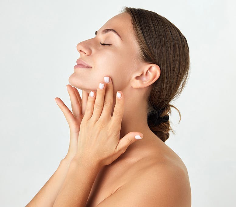 woman rubbing her neck while her head is tilted up