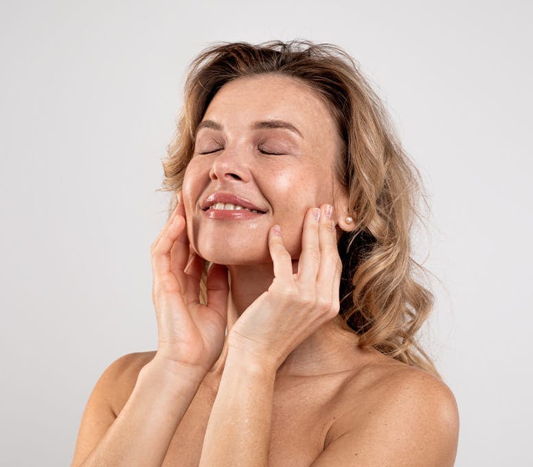 woman touching her face and smiling while looking upwards
