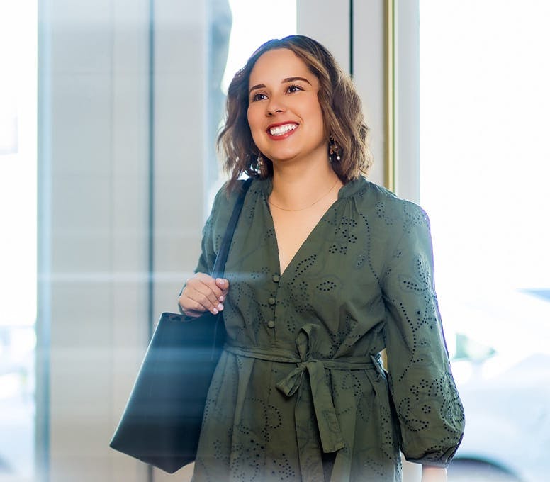 woman in green top with purse smiling