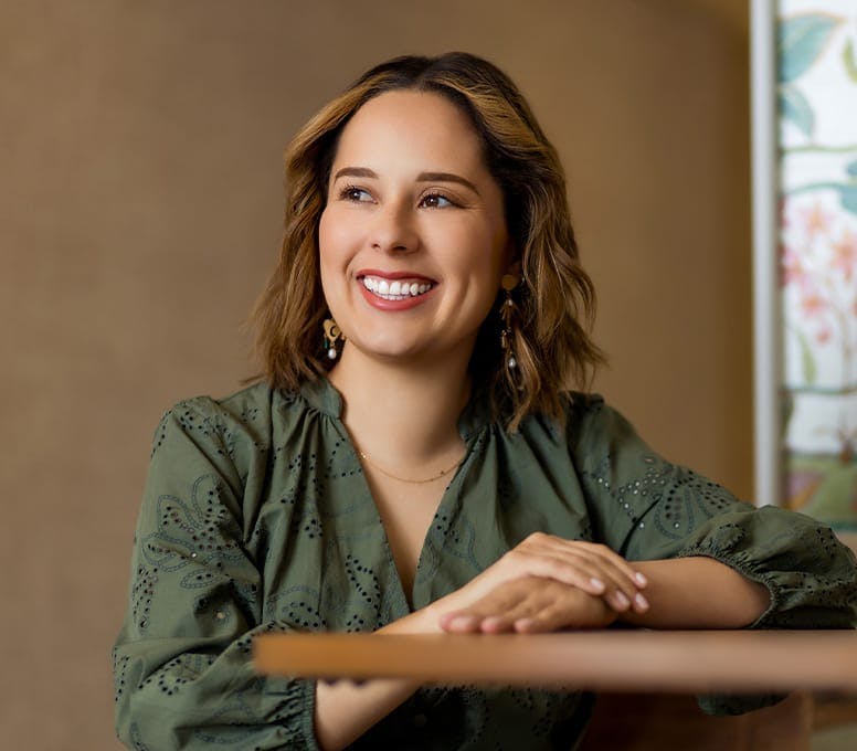 woman in green resting hands on table and smiling