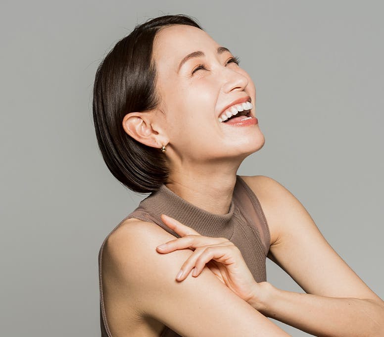 woman laughing/smiling while grabbing her own arm