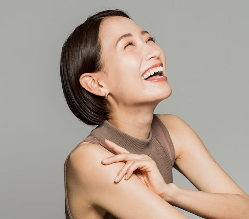 woman laughing/smiling while grabbing her own arm