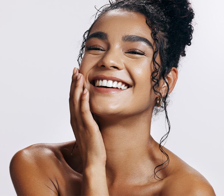 woman with bun in hair smiling and touching her cheek