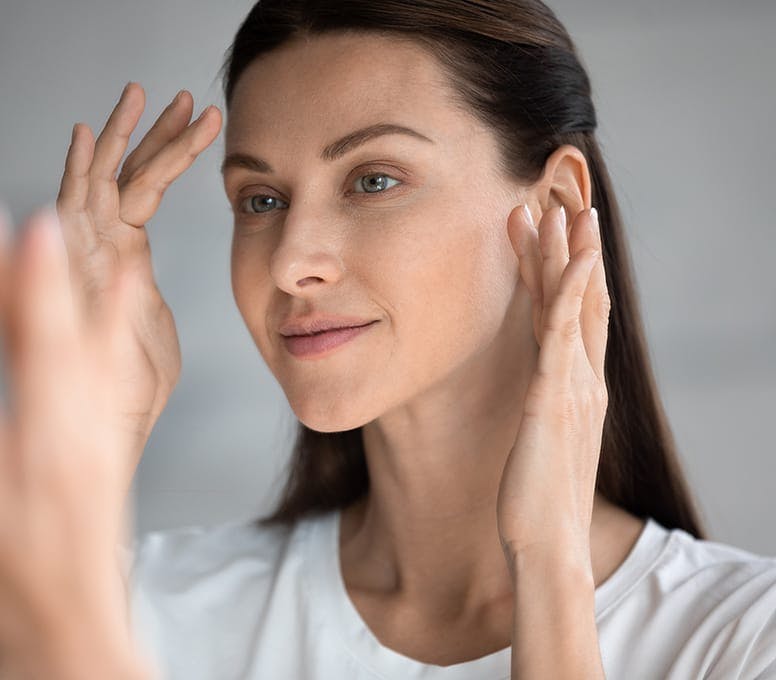 woman looking in mirror about to touch her face