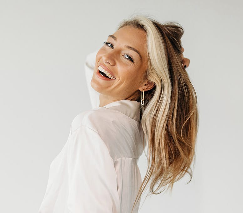 woman in white top smiling and looking over her shoulder