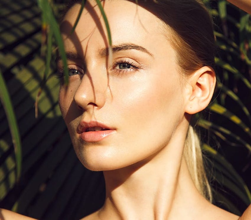 sun hitting the woman's face with a plant in front of her
