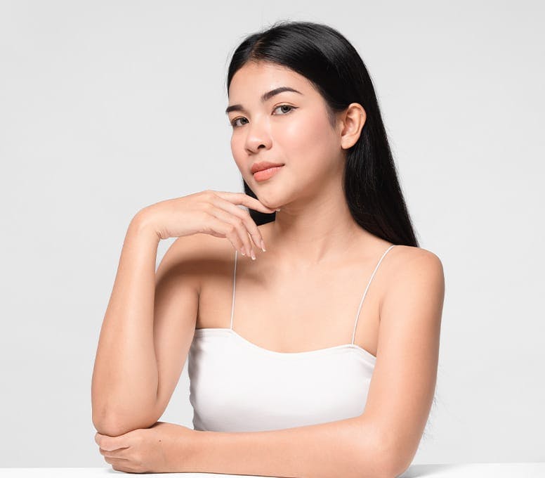 woman in white tanktop resting her arm on the table
