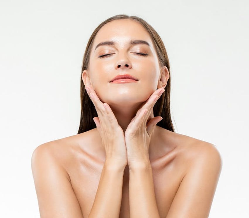 woman with her eyes closed with head up touching her jaw line with both hands