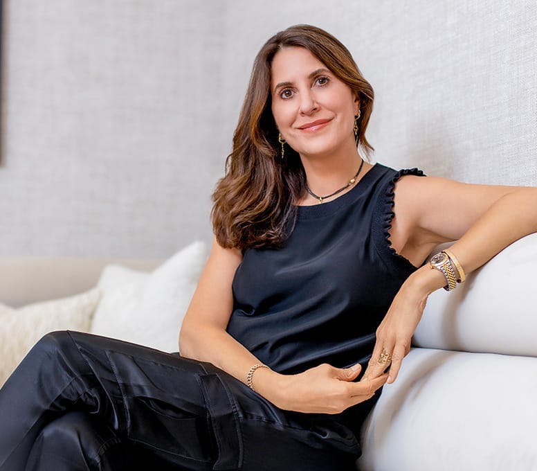 Linda Belha in black dress sitting on couch