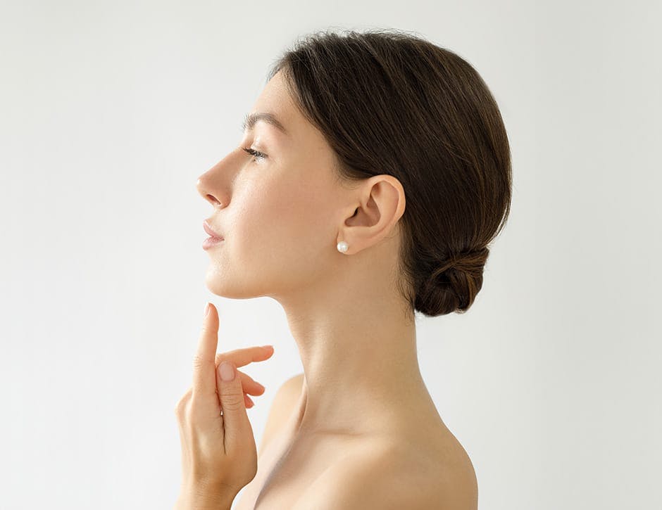 side profile of woman pointing to her chin