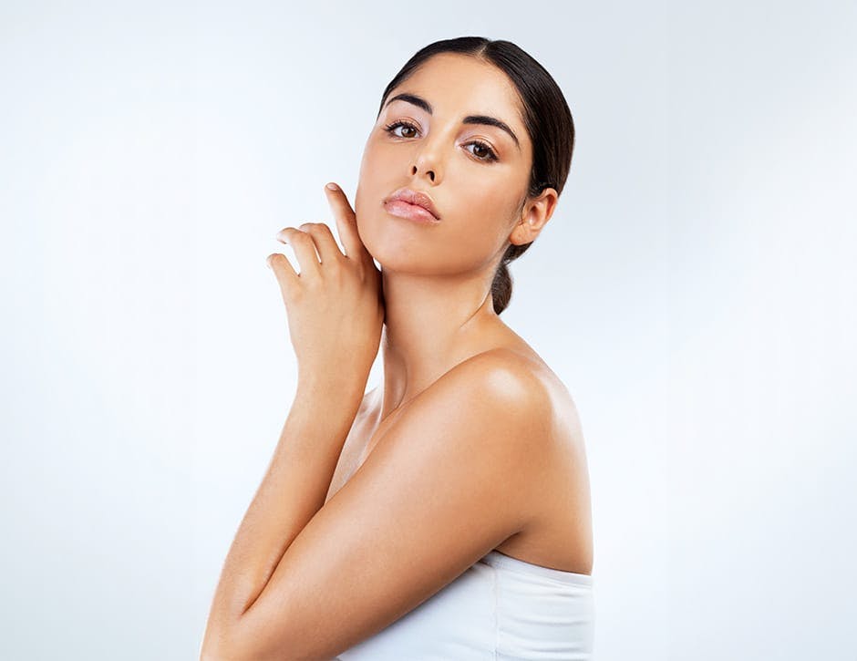 woman with hand places near her jaw in white top