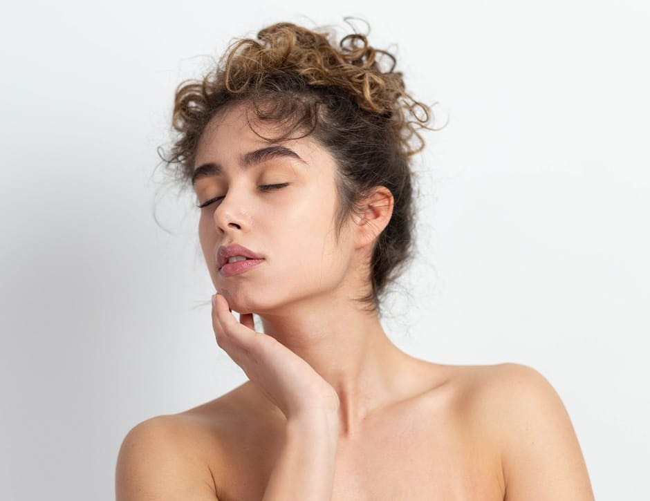 woman with curly hair tied up with hand on her chin