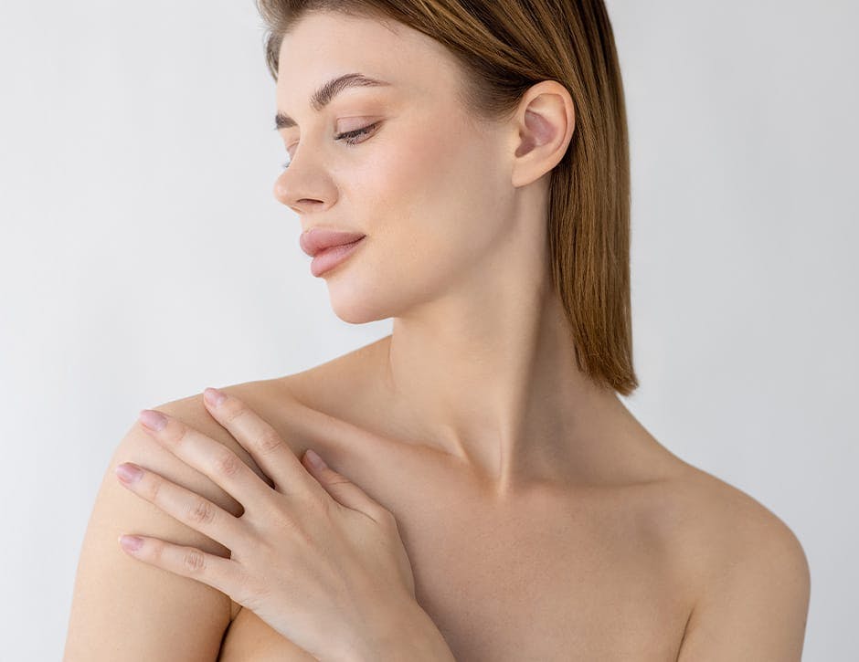 woman with short hair looking to her left and touching her shoulder