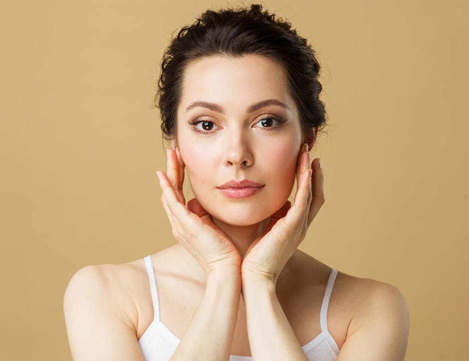 woman with both of her hands touching her jaw