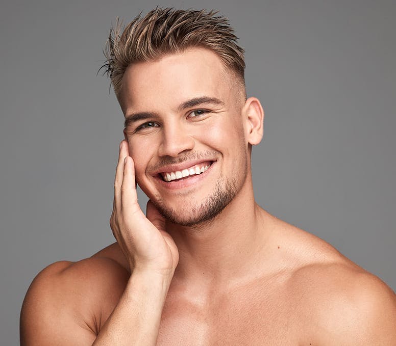 man smiling while he touches his cheek