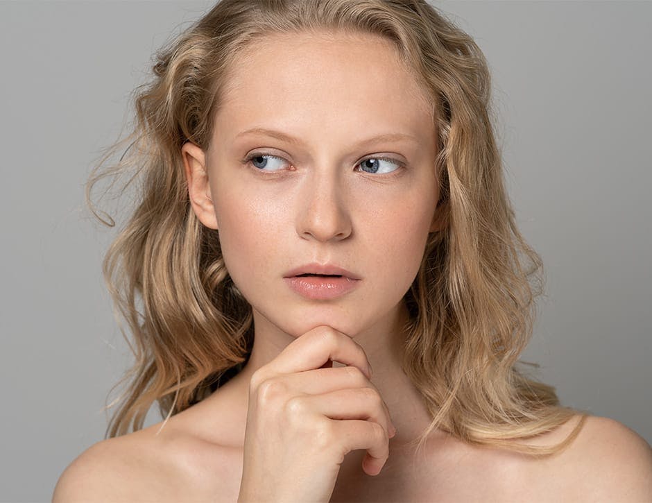 woman looking to the left with her grabbing the tip of her chin