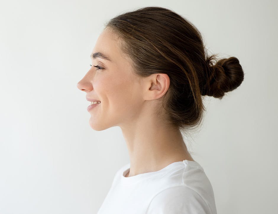 side profile of woman smiling with hair in a bun