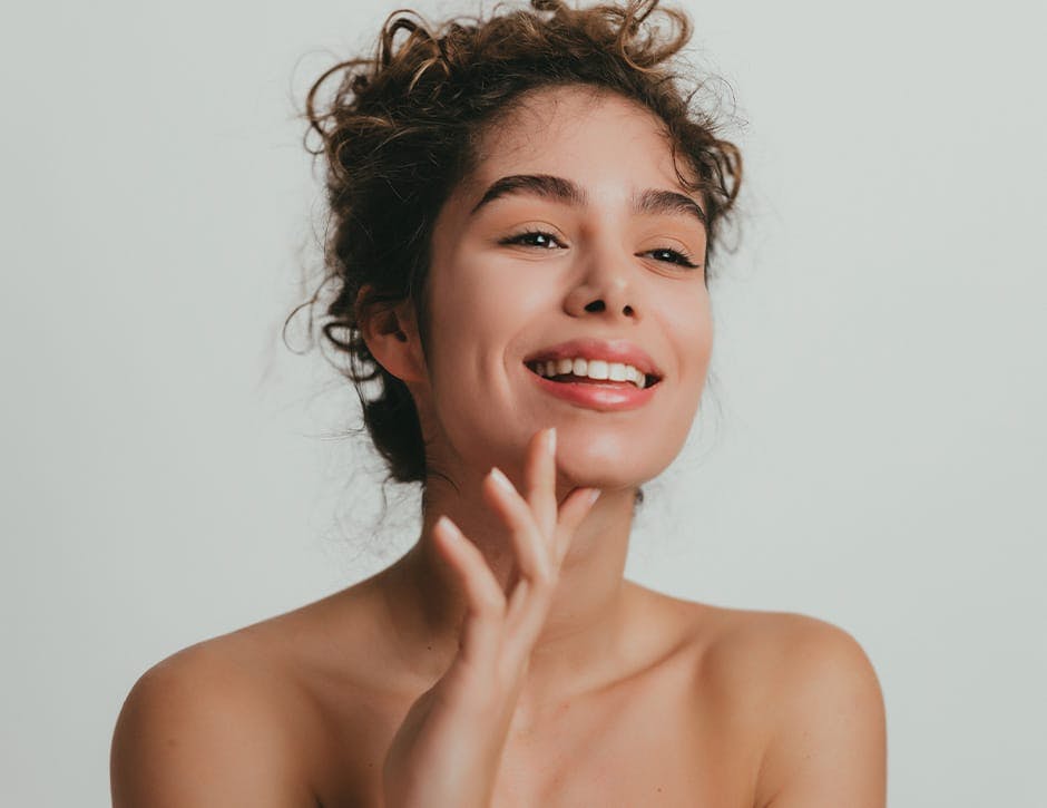 woman with curly up-do with finger touching under her chin