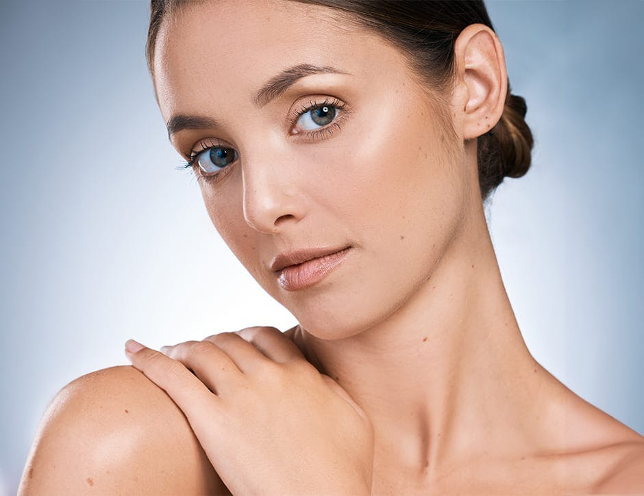 woman with hair up touching her shoulder