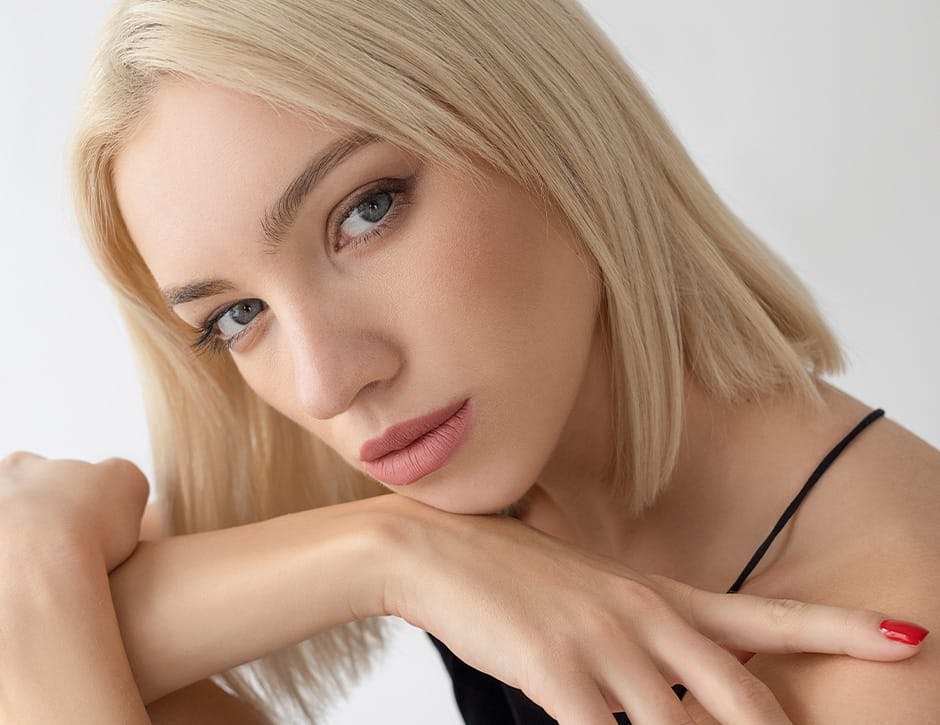 woman with short blonde hair tilting her head and resting chin on her arm