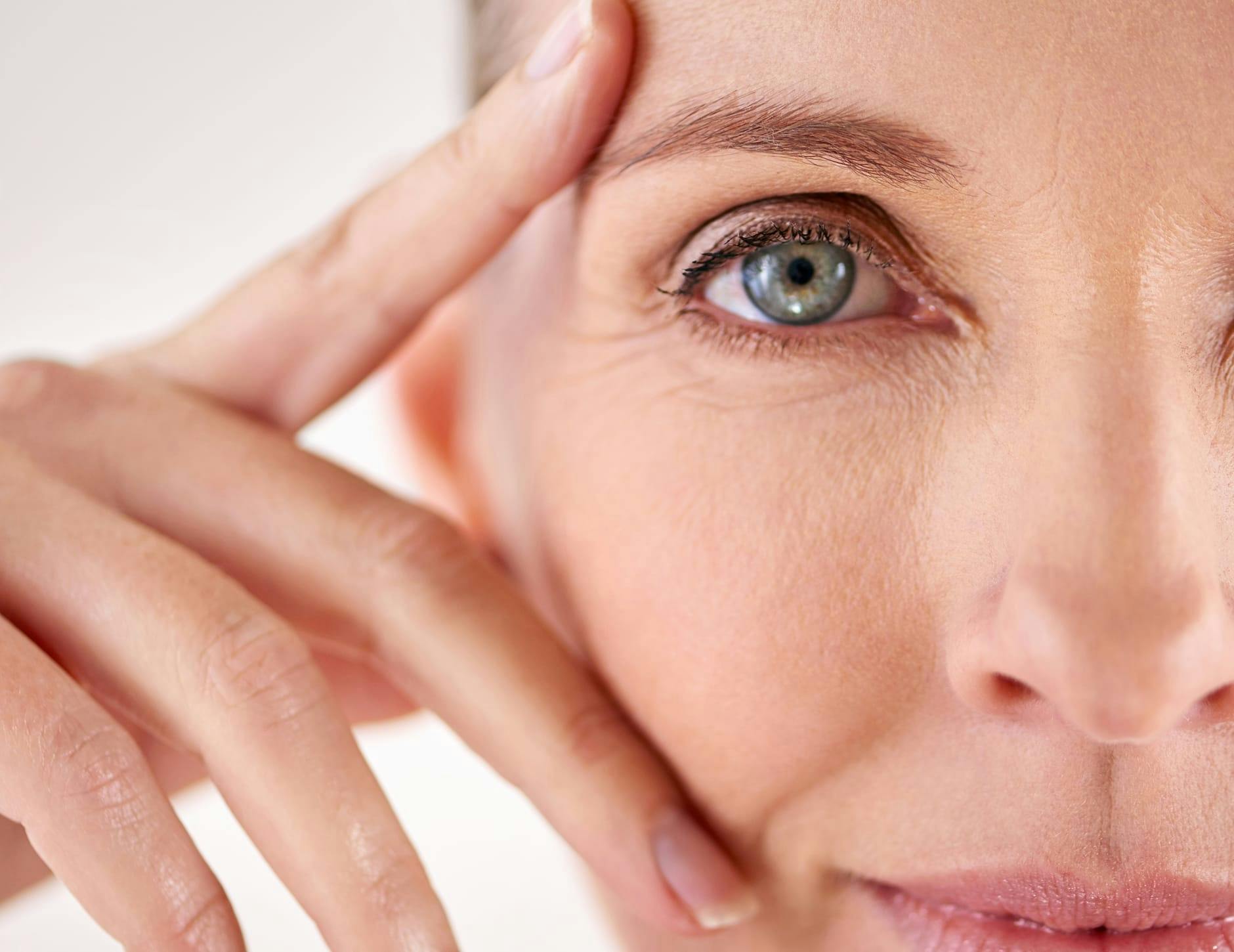 close up of half of woman's face with her fingers around her eye