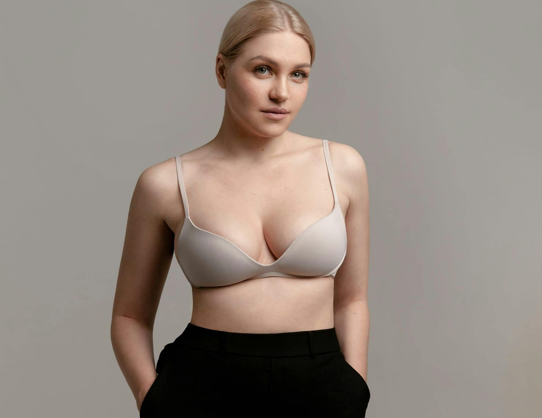 woman in bra and black pants with hands in the pockets