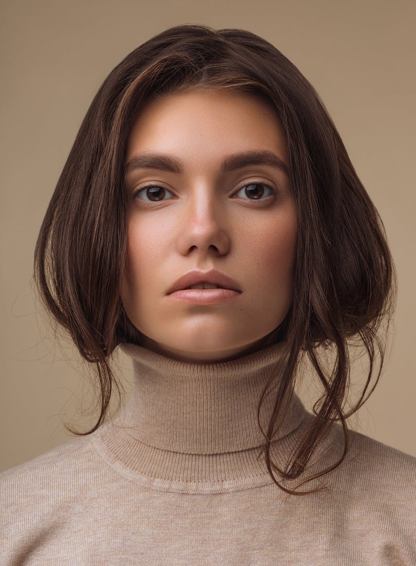Woman with beautiful skin and brown hair tucked into the turtleneck she's wearing