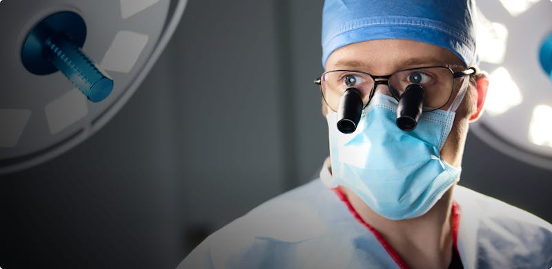 Dr. James Goggin wearing surgical loupes and scrubs in the operating room.