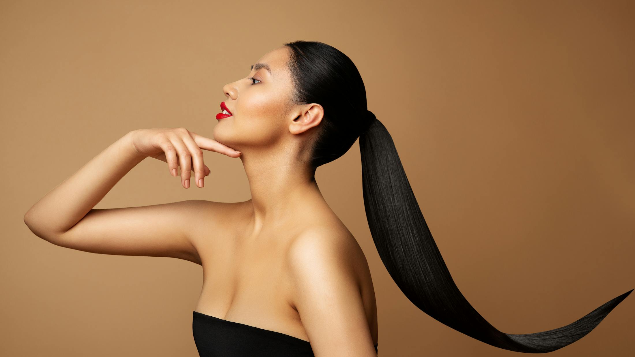 A woman with a black ponytail touching her face
