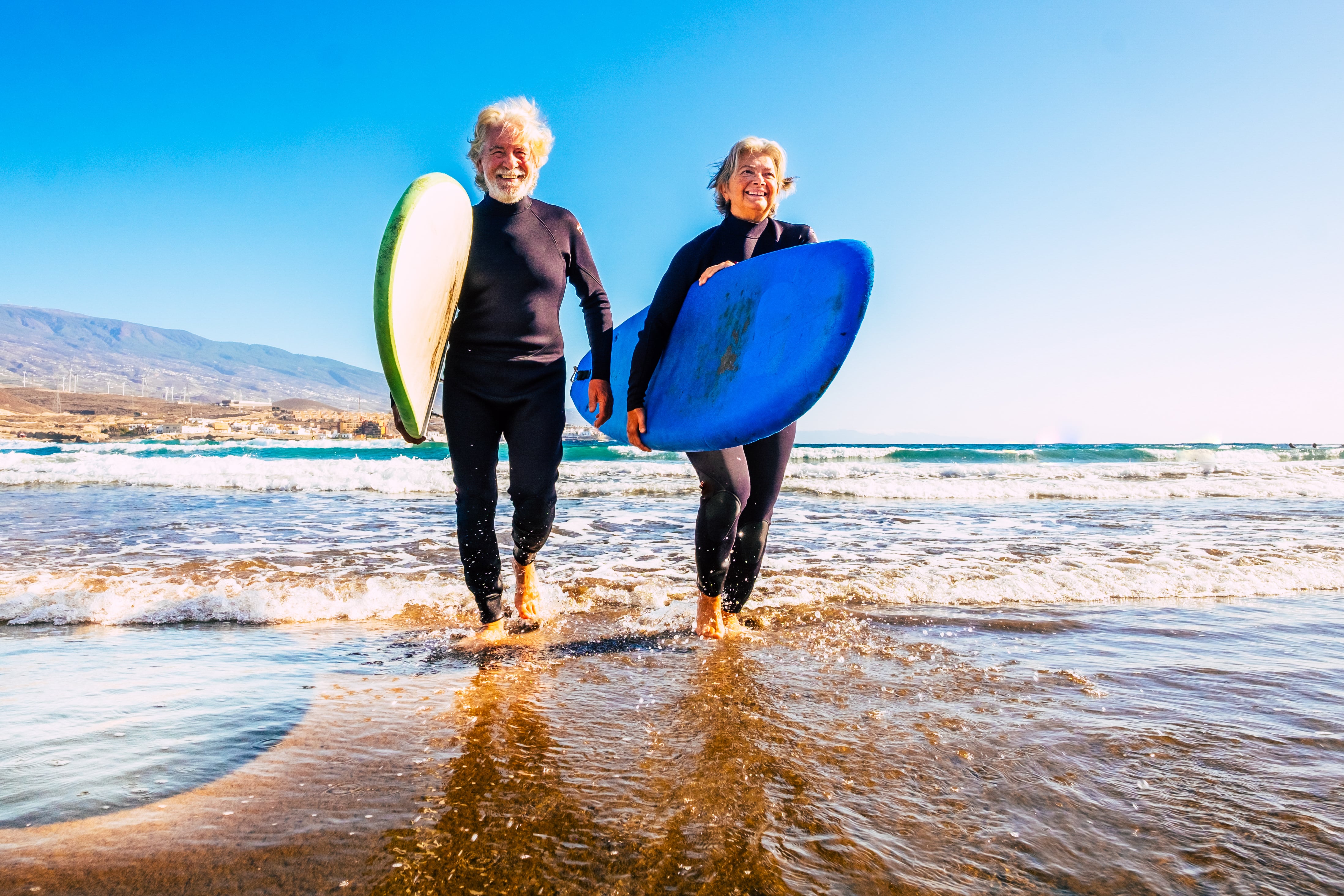 An elderly couple on the beach surfing