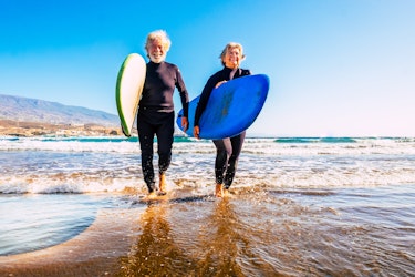 An elderly couple on the beach surfing