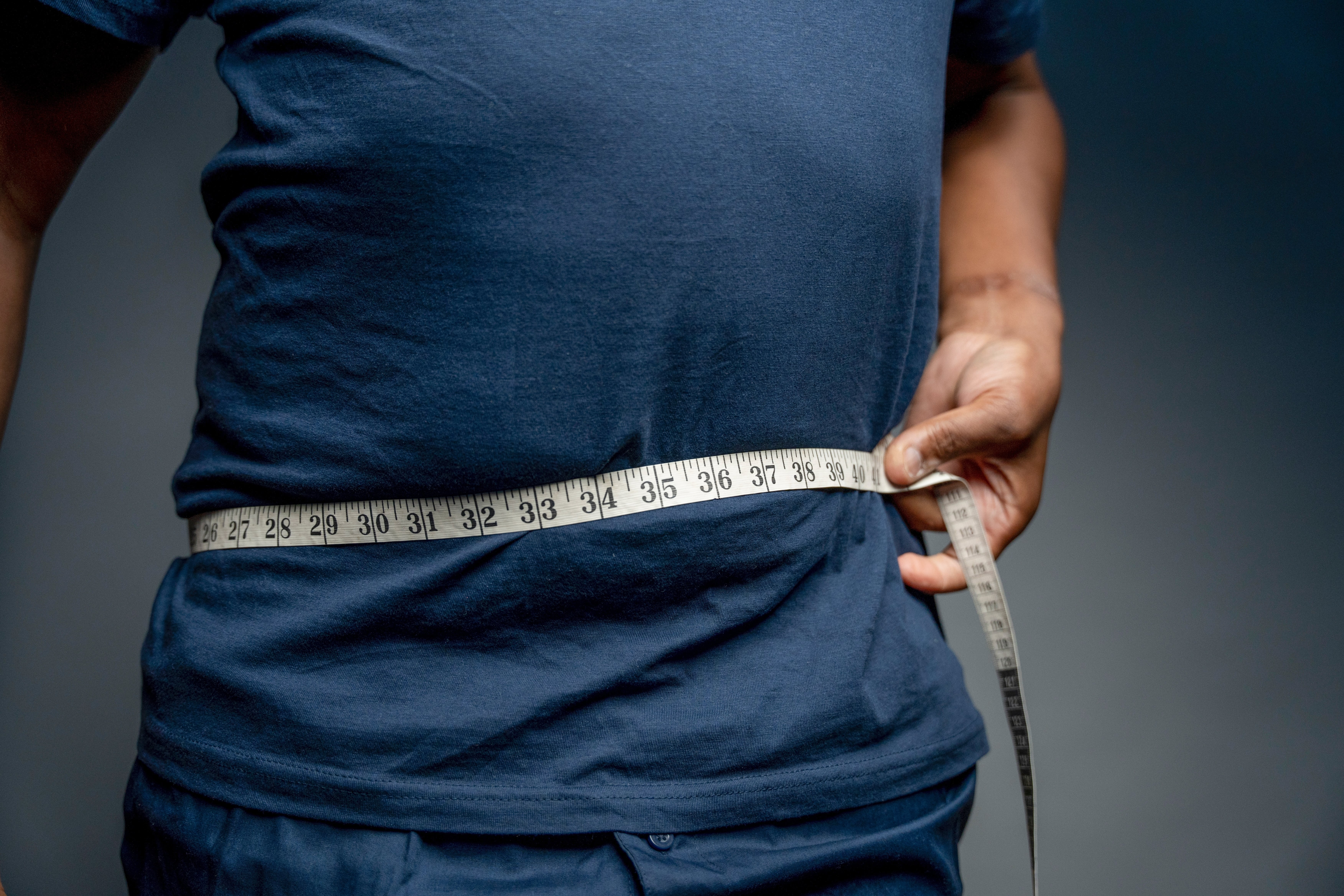 A man with a tape measure wrapped around his gut